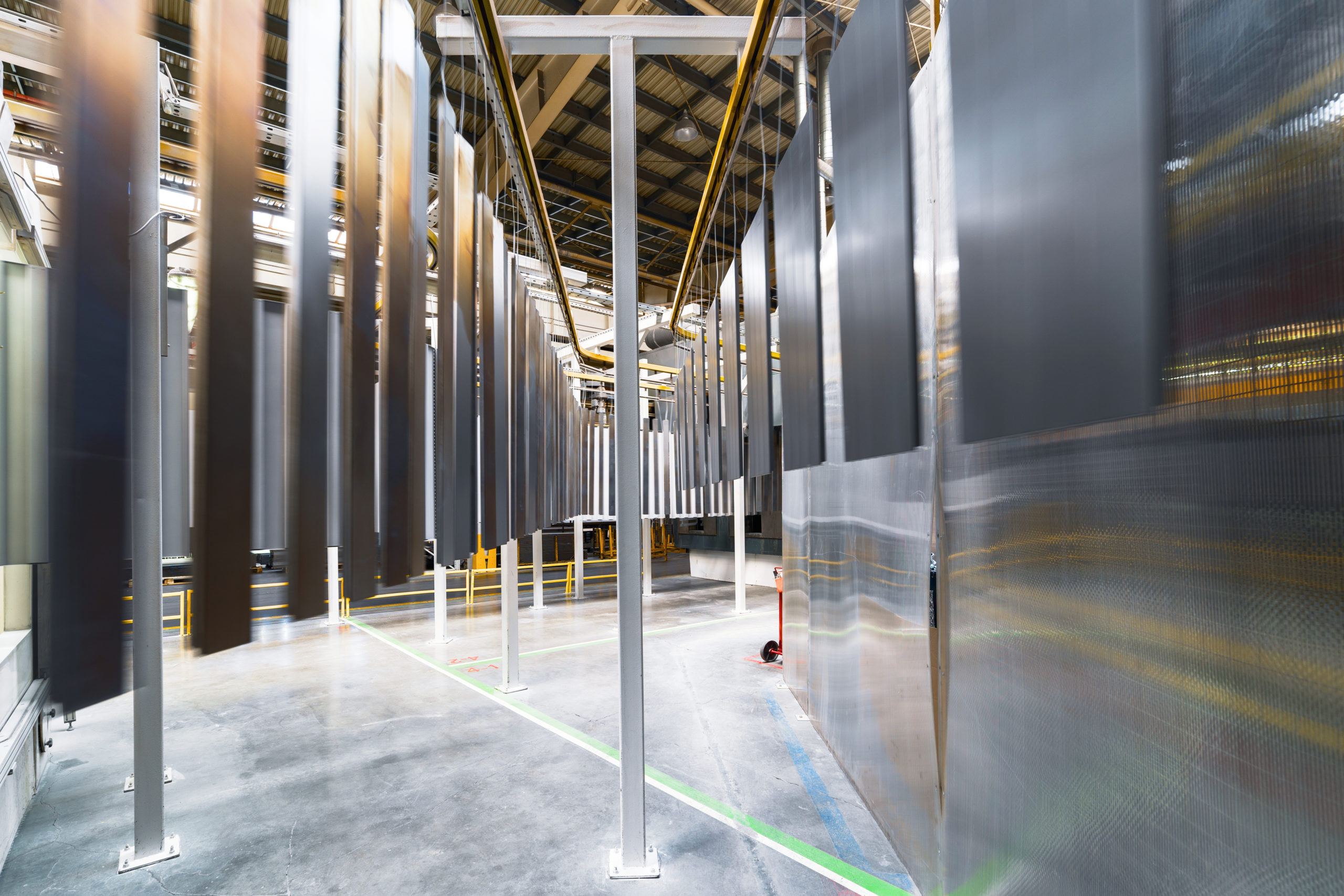 Powder coating line. Metal panels are suspended on an overhead conveyor line.