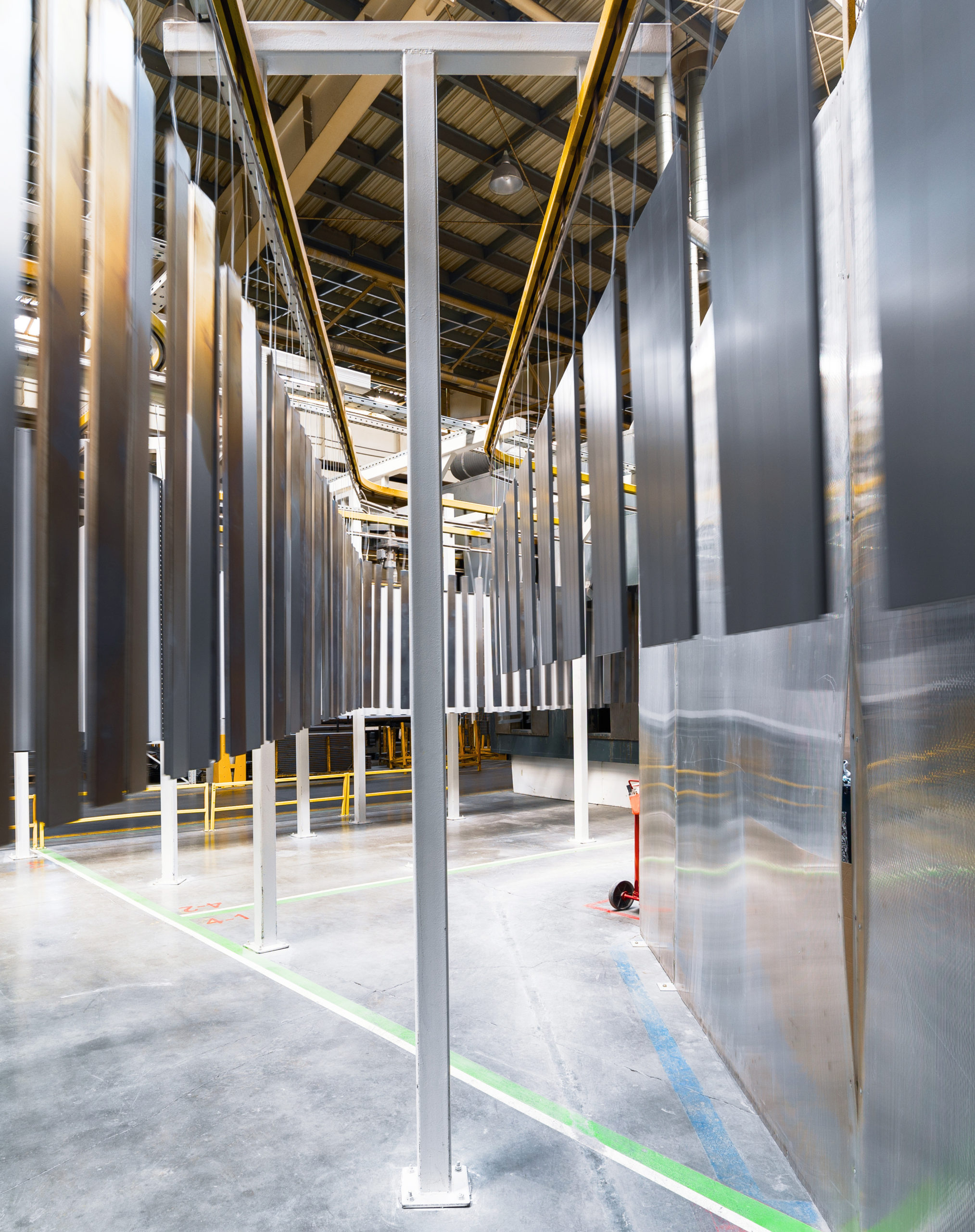 Powder coating line. Metal panels are suspended on an overhead conveyor line.